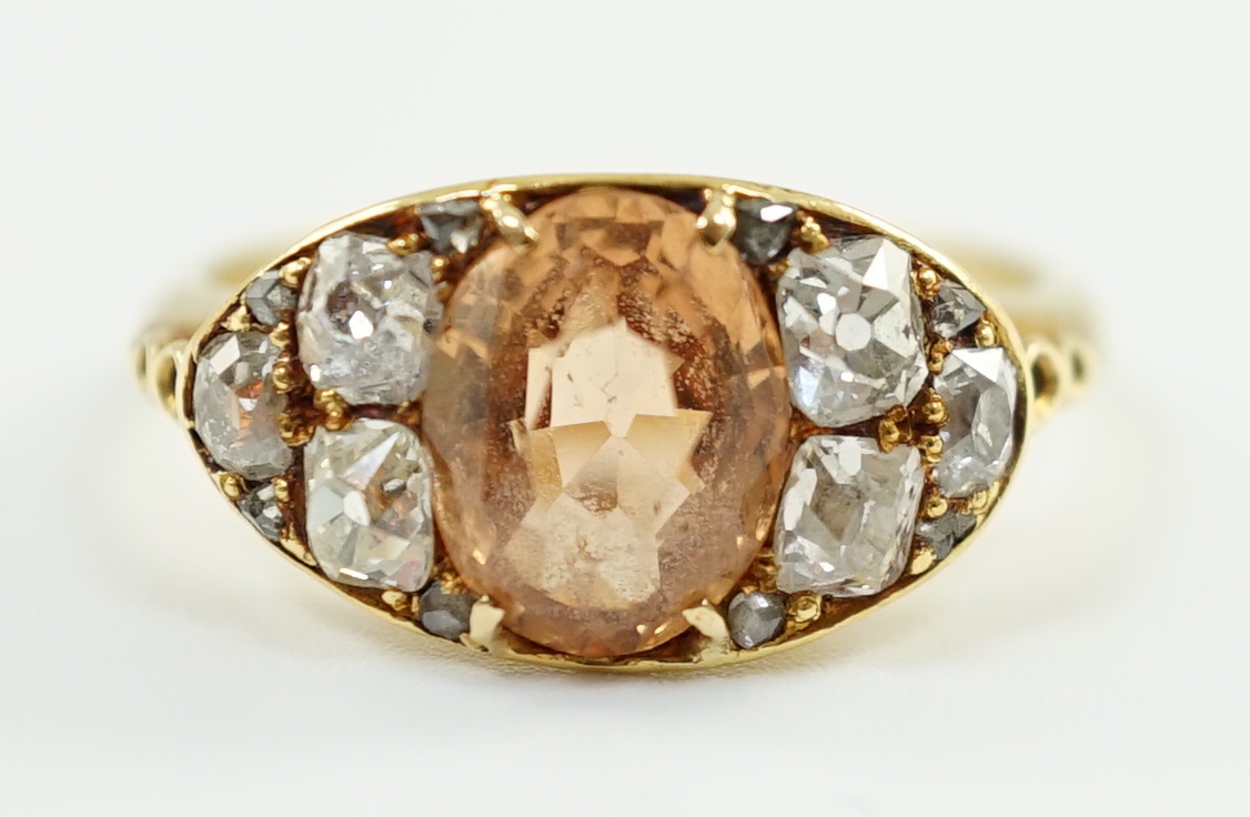 A 1940's gold and single stone oval cut orange topaz set ring, with six stone old mine cut diamond set shoulders